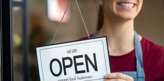 Refund Fight Fuels Discrimination Uproar Shop worker holding an open sign
