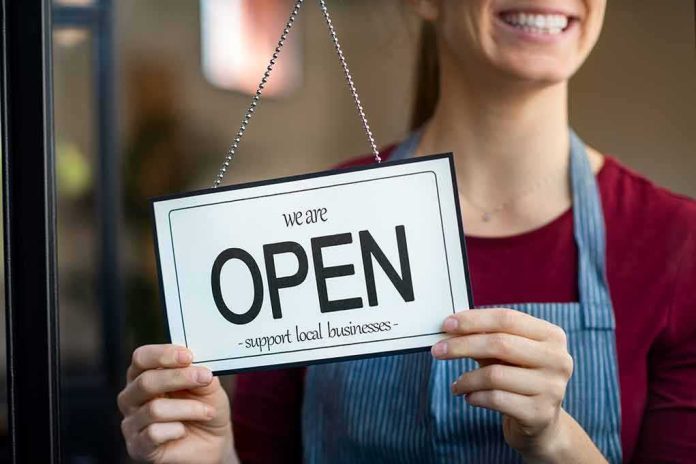 shutterstock_1714676551 Shop worker holding an open sign