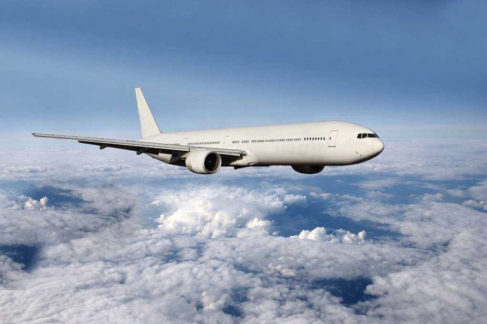 shutterstock_182272232 A white airplane flying above fluffy clouds in a blue sky