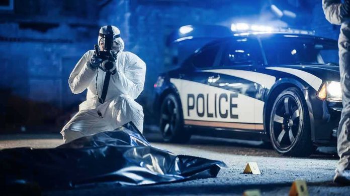 shutterstock_2230642401 forensic investigator photographing crime scene near police car