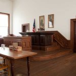 Dem Star Jailed Again — Meth Bombshell Interior of a historic courtroom with wooden furniture and an American flag