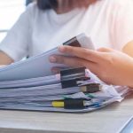 $40M Gold Vanishes – Timecards Take Him Down Person organizing a stack of documents with binder clips