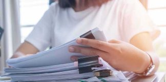 $40M Gold Vanishes – Timecards Take Him Down Person organizing a stack of documents with binder clips