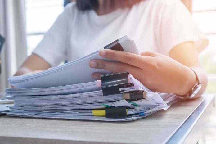 Person organizing a stack of documents with binder clips
