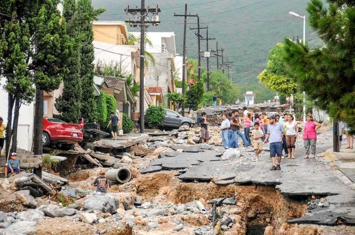 Residents walk along a heavily damaged street after a disaster