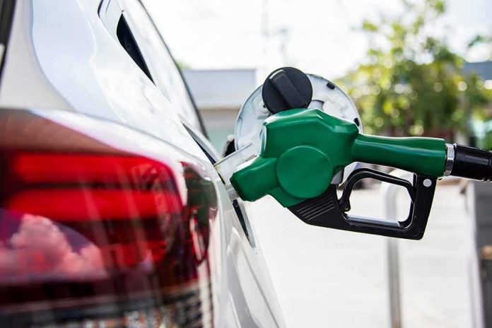 shutterstock_1281520942 Green fuel nozzle pumping gas into a white car