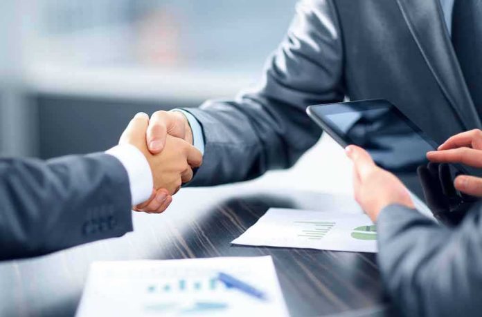 Businesspeople handshake at meeting table