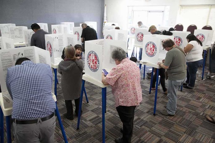 shutterstock_133686017 Voters fill out ballots at polling booths in a busy voting room