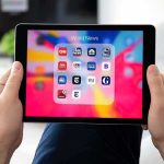 Taxpayer Millions Fund Inmate Porn Access! Hands holding a tablet showing a folder of world news apps