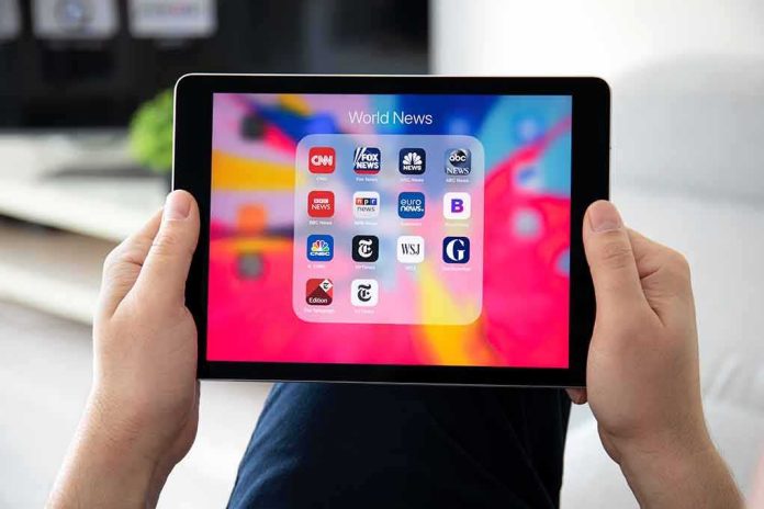 shutterstock_1354868951 Hands holding a tablet showing a folder of world news apps