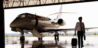 Pilot walking with suitcase beside private jet in hangar