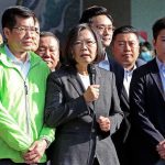 Tsai Ing-wen speaks into a microphone beside Arthur Dong in a group of people outdoors