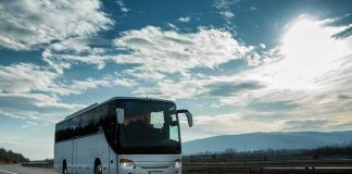 White coach bus driving on a highway under a bright sky