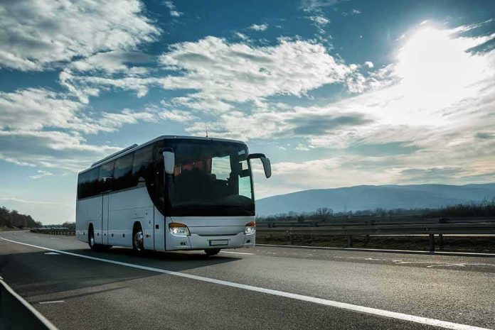 White coach bus driving on a highway under a bright sky