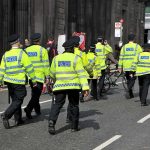 Teen Girl Arrested After School Stabbing Police officers in high-visibility jackets walking on a city street