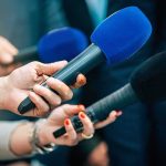 Carrier Vanishes: 16-Month West Coast Gap Reporters holding colorful microphones