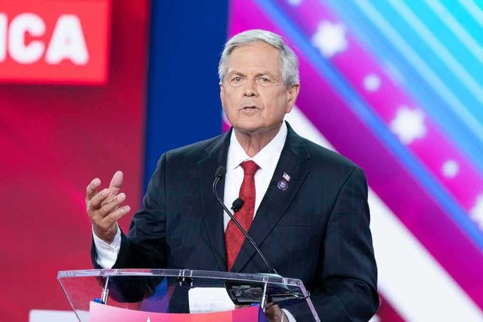 Man in suit speaking at a podium on a colorful stage