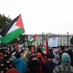Tour Opener Turns Political Flashpoint Crowd holding flags and signs outside a fenced government building
