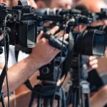 Court Halts Controversial Ebola Base television cameras on tripods at a media event