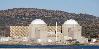 Nuclear Blindspot Widens – IAEA Frozen Out Nuclear power plant with domed structures beside a water body and mountains in the background