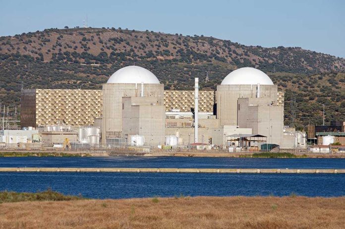 shutterstock_4217311 Nuclear power plant with domed structures beside a water body and mountains in the background