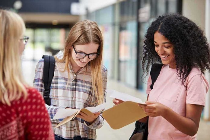 shutterstock_763468423 Students smiling while reading papers in a school hallway
