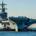Pentagon Glory, Congress Smells Smoke Aircraft carrier guided by tugboats in a harbor