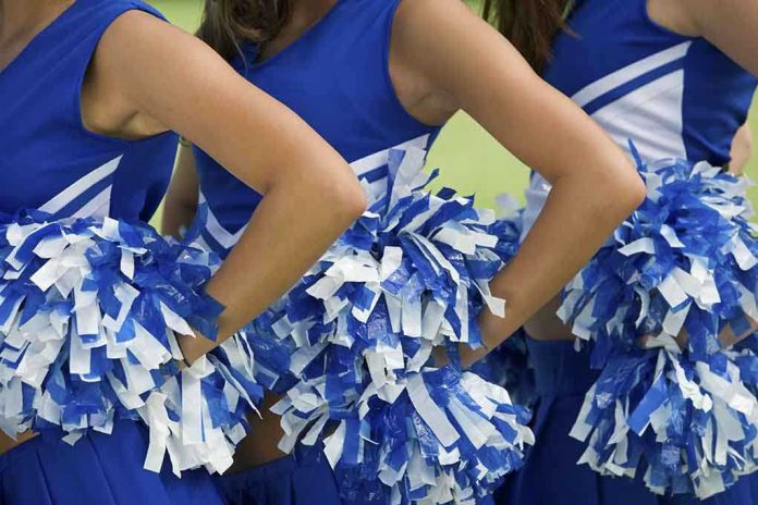 shutterstock_109441577 Cheerleaders in blue and white uniforms holding pom poms