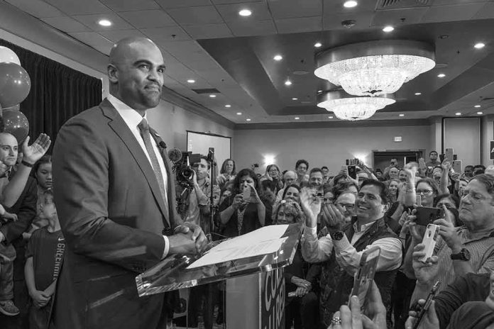 shutterstock_1223867530 Colin Allred speaks at a podium as Christian Jones and a crowd applaud