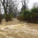 California Beaches Drown – Storm Never Lands Flooded residential street with fast-moving muddy water