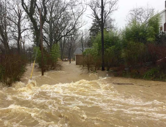shutterstock_1321316804 Flooded residential street with fast-moving muddy water