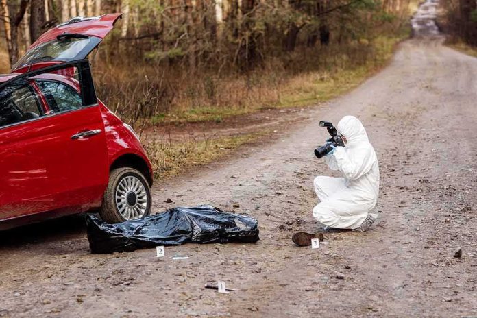shutterstock_1373214479 forensic investigator photographing evidence near red car on dirt road