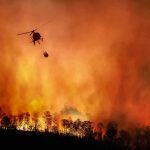 Porch Flick Sparks 1,000-Acre Federal Nightmare Helicopter fights massive wildfire over burning forest