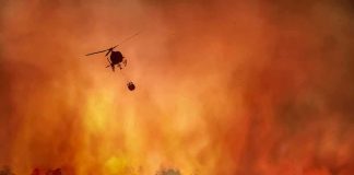 Porch Flick Sparks 1,000-Acre Federal Nightmare Helicopter fights massive wildfire over burning forest
