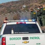 Judge Slams Brakes On Big Bend Build Border Patrol agents gather near fence with patrol trucks
