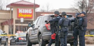 Officer Resigns as Deadly Footage Emerges Police officers gather beside a patrol SUV at a taped-off scene