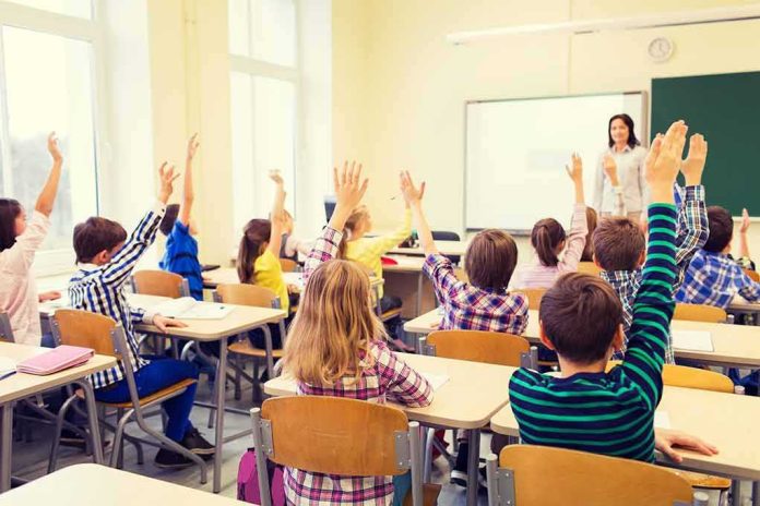 Students raise hands in a classroom with a teacher at the front