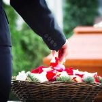 Hollywood Mourns: Beloved Actor, 34 Person in black suit placing rose petals from basket near coffin
