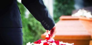 Hollywood Mourns: Beloved Actor, 34 Person in black suit placing rose petals from basket near coffin