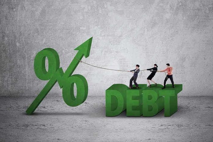 shutterstock_374037043 Three people pulling rope tied to rising percent sign beside large debt text