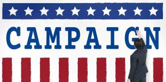 Awkward Reunion: Obama Meets His Critic Man in suit writing on large campaign banner with stars and stripes