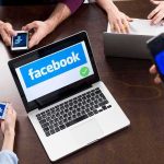 Whistleblower Torches Facebook’s Profit Playbook Laptop with Facebook on screen surrounded by smartphones