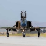 Military jet taxiing on runway with open canopy
