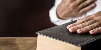 Cease-And-Desist Bomb Hits Senate Fight Hand on a thick black hardcover book on a wooden table